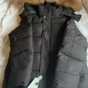 Svart dunjacka från Canada Goose passar S/M och jag kan byta med den. - Säljer en svart dunjacka från Canada Goose med huva och avtagbar fuskpäls. Jackan har klassisk patch på ärmen, dragkedja och knappar framtill samt två stora fickor. Perfekt för kalla vinterdagar och riktigt snygg passform och priset kan diskuteras och bytte kan jag.