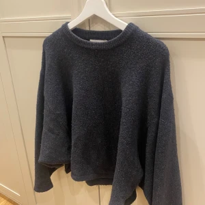 Mörkblå stickad tröja Carin Wester - Mysig mörkblå stickad tröja från Carin Wester i storlek S. Tröjan har en loose passform, rund halsringning och långa ärmar. Perfekt för dig som gillar en chill och avslappnad stil med lite oversized känsla.