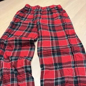 Flanell Röd-rutiga mjukisbyxor från H&M - Säljer ett par sköna flanell mjukisbyxor från H&M i storlek 158. Byxorna är röd-rutiga med svarta och vita detaljer, har resår i midjan och är tillverkade i 100% bomull. Perfekta för chill hemma eller häng med kompisar.