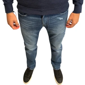 Jeans - Levi's 502  - Säljer ett par klassiska Levi's 502 jeans i blå tvätt med snygga slitningar och raka ben. Jeansen har fem fickor, normal midja och den ikoniska röda Levi's-taggen bak. Perfekt passform för dig som gillar en tidlös och avslappnad stil.