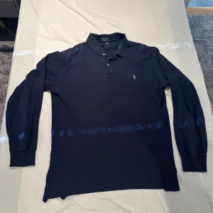Långärmad pikétröja Polo Ralph Lauren - Klassisk marinblå långärmad pikétröja från Polo Ralph Lauren. Tillverkad i 100% bomull för en skön och avslappnad känsla. Fint skick, storlek L.