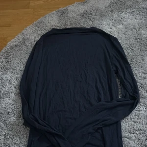 Svart långärmad tröja från Missay - En enkel och stilren svart långärmad tröja från Missay. Tröjan har en klassisk passform och är tillverkad i ett mjukt och tunt material som passar perfekt till lager-på-lager. Perfekt basplagg för garderoben.