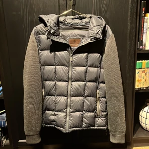 Massimo dutti cardigan - Säljer en svart cardigan från Massimo Dutti med quiltad kropp och stickade ärmar. Jackan har huva, dragkedja framtill och två fickor med dragkedja. Perfekt för kyliga dagar.