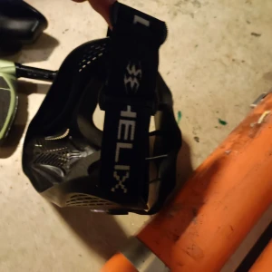 Paintball pistol mask och luftuber - Paintballmask från Empire Helix i svart med justerbart band och ventilerad design för bra andning. Masken har en stor lins som ger bred sikt och skydd för hela ansiktet. Perfekt för dig som vill ha stil och funktion på paintballbanan.