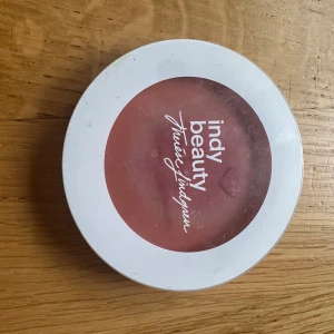 Indy Beauty rouge Make Me Blush Jasmine - Rouge från Indy Beauty i nyansen Jasmine. Kommer i en rund vit dosa med genomskinligt lock. Färgen är en varm, rosabrun ton som ger kinderna en fräsch och naturlig look. 100% vegansk formula. Perfekt för att ge ansiktet lite extra glow. Den är swatched, se sista bild 