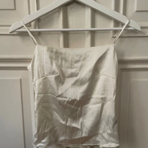 Vit satin linnetopp med knyt - Säljer min supersnygga satin linnetopp, man knyter den i ryggen och väljer längden på axelbanden så den passar alla!! Köp nu jag postar snabbt!!💓💓💓