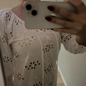 Vit blus med blomdetaljer  - Säljer en söt vit blus med fina blomdetaljer fram och bak på blusen!