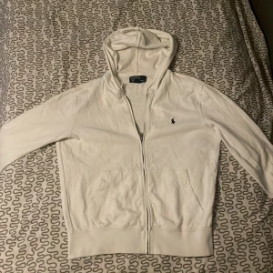 Vit Ralph lauren hoodie  - Säljer en vit Ralph lauren hoodie med luva och dragkedja den är nästan helt ny har bara testat den 1 gång så i väldigt fint skick hör av er vid frågor och kan bli billigare vid snabb affär 