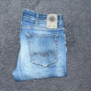 Replay Jondrill jeans - Säljer ett par Replay Jondrill jeans i snyggt ljusblå tvätt med slitningar och klassiska fem fickor. Modellen är skinny fit med låg midja och raka ben. Jeansen har Replay-logga på bakfickan och etikett i linningen. Midja 42cm, längd 106cm. JAG SKICKAR EJ FLER BILDER NÄR JAG BÄR JEANSEN! för storleksguide hänvisar jag till måtten och för bättre inblick i passformen rekommenderar jag att googla på modellnamnet. Jeansen kan vara uppsydda utan att jag noterat det så kolla måtten noggrant:). 30