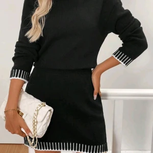 Svart stickad kortklänning med vita detaljer - Supersnygg svart stickad kortklänning från Frenchy med vita ränder vid hals, ärmslut och nederkant. Klänningen har lång ärm och en rak, normal passform som sitter bekvämt. Perfekt för dig som gillar stilrena och trendiga plagg med en twist.