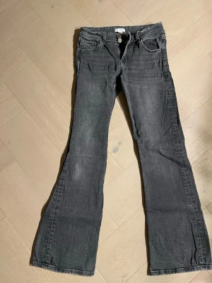 Bootcut jeans från Gina Tricot, grå - Säljer ett par gråa bootcut jeans från Gina Tricot i storlek 158. Jeansen har klassisk femficksdesign, knapp och dragkedja framtill samt snygga sömmar. Materialet är mjukt och följsamt jeans-tyg som ger en chill vibe till din outfit.