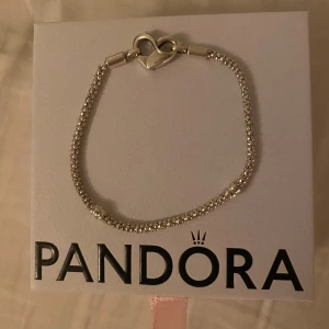 Pandora silver armband - Säljer ett superfint & snyggt armband från Pandora i sterlingsilver (äkta silver) med ett hjärtformat lås😻Kedjan är flätad/dubbad och har en glansig finish som ger en lyxig känsla. Perfekt att matcha med andra smycken eller bära som det är! Kommer i original ask dessutom💞Bra basarmband till framtida olika charms om man vill! Använd någon gång, inga defekter🫶🏻Orginal pris är 899kr. 