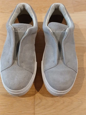 Eytys  - Snygga grå sneakers från Eytys i mocka med vit sula och en lila detalj baktill. Perfekta för dig som gillar stilrena och bekväma skor. Pris går att diskuteras.