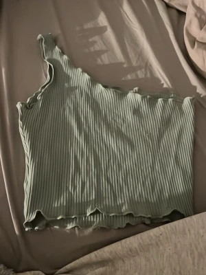 Ljusgrön ribbad oneshoulder topp - Säljer en ljusgrön ribbad topp med oneshoulder-design. 