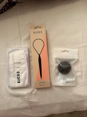 Skönhetsprodukter - Set med en vit sminkborste i form av ett pannband, en svart konjacsvamp och ett loop tool från KICKS. Pannbandet är i mjukt frottématerial, svampen är rund och svart, och loop tool är svart med lång handtag. Perfekt för din sminkrutin.