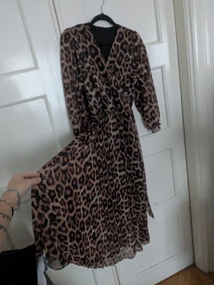 Leopardmönstrad långklänning - Säljer en snygg långklänning med leopardmönster och v-ringad omlottfront. Stl S , använd några gånger bara 