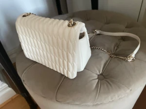 Vit quiltad axelväska med kedja - Snygg axelväska i vit färg med quiltad design och guldfärgad kedjerem. Så himla snygg! Inga tecken på användning! 