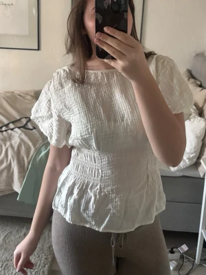 Vit blus med smock  - Säljer en vit blus med volangärmar och har smock i midjan, storlek M, inga defekter (inga hål, fläckar osv) från H&M!