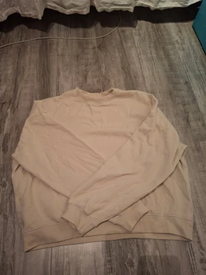 Beige sweatshirt - Säljer en enkel beige sweatshirt med rund hals och långa ärmar från weekday. Andvänd en gång och är i fint/nytt skick.  Marknasförs för kvinna på weekdays hemsida men jag tror tröjan kan passa både kvinnor och men! Storlek M och är i loose fit/ganska baggy. Köpt för ca 400kr, priset kan förhandlas! 