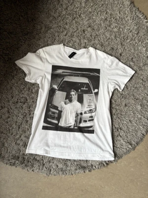Vit t-shirt med biltryck från H&M - Vit tisha med tryck av Paul walker, den e nästan ny utan slitage o fläckar perfekt för dig som vill liva upp en vanlig vit tisha. 