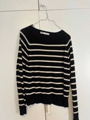 Svartvit randig tröja från Zara - Säljer en svart och vit långärmad tröja från Zara i storlek S. Tröjan har ett klassiskt horisontellt randigt mönster och är tillverkad i mjukt stickat material. Perfekt för dig som gillar enkel och stilren design med en chill vibe.