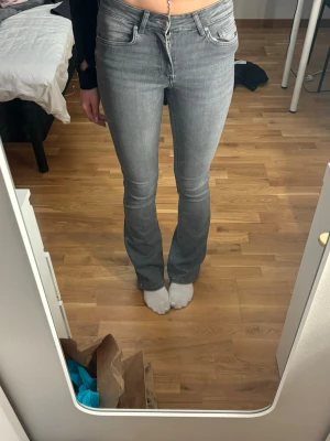 Grå bootcut jeans från ONLY, S - Säljer ett par grå bootcut jeans från ONLY i storlek S. Jeansen har klassisk femficksdesign, normal passform och är tillverkade i mjukt denim-material. Snyggt smalare upptill och lite utsvängda nedtill för en trendig look.