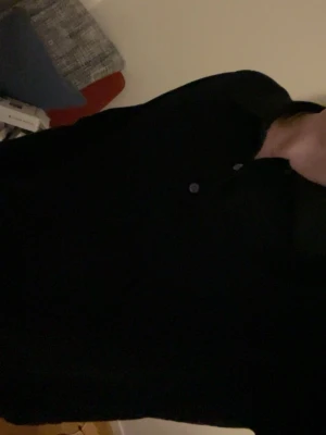 Svart pikétröja från Massimo Dutti - Säljer en stilren svart pikétröja från Massimo Dutti i 100% ull. Tröjan har lång ärm, klassisk krage och knappar framtill. Passformen är normal och materialet är mjukt och skönt mot huden. Perfekt för dig som gillar enkel och snygg design .                                                                                     Kan skicka fler bilder om de behövs 😊.       storleken är small jag e 180                              Priset är prut bart