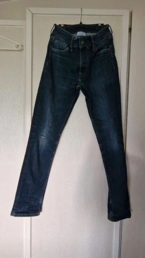 Mörkblå jeans från Valient - Slitage på höger knä där det har gått hål men även vid sömmen på insidan ner vid fötterna på vänster sida. Stl W29 L32