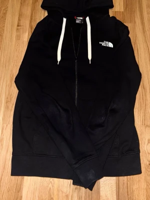 Svart The North Face zip hoodie - Otroligt skön, känns som ny, ända täcken på användning vid är vid märket på bröstet. Annars är tröjan i väldigt bra skick.