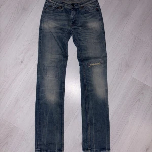 Blå straight jeans från acne  - Blå straight fitted jeans från acne studios med coolt broderi på ett knä och nice distressing på andra, byxorna har inga skavanker och är i praktiskt taget nytt skick. Storlek w26L32. Självklart går priset att diskutera vid snabb och smidig förhandling!