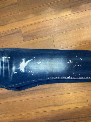 Mörkblå  jeans -  mörkblå jeans  med coolt distressed utseende, slitningar och vita färgstänk. Klassisk femficksmodell , Jeansen har en rak passform och är tillverkade i stretchig bomull.