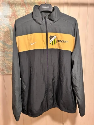 BK Häcken Nike jacka, storlek XL - Mycket gott skick!  Jacka i grått och gult med B.K Häcken logga och Stadium tryck på bröstet. Nike logga finns också på bröstet och i nacken.