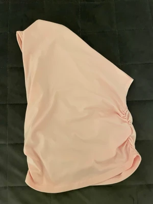Ljusrosa one shoulder tubtopp - Säljer en ljusrosa tubtopp i one shoulder-modell med lätt rynkdetalj på sidan. Toppen är stilren och enkel, perfekt att matcha med jeans eller kjol. Materialet känns mjukt och stretchigt, vilket gör den bekväm att bära hela dagen. Helt ny, aldrig använt den. Angående frågor är det bara att höra av sig, samma gäller diskutioner kring priset.