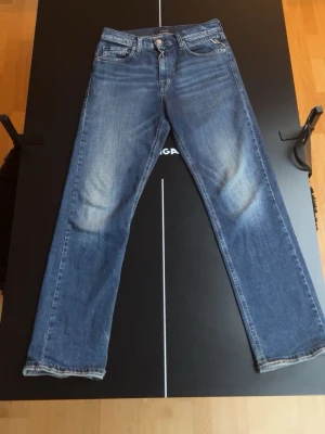 Blå Replay jeans Thad straight fit - Säljer ett par klassiska blå jeans från Replay, modell Thad. Jeansen har en rak passform, fem fickor och snygga slitningar framtill. Tillverkade i slitstarkt denim med Replay-logga på bakfickan och patch i midjan. Perfekta till vardagslooken. Skriv vid frågor
