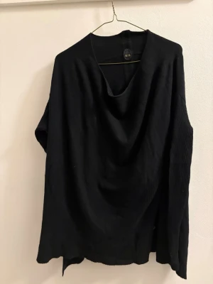 Svart oversized stickad tröja Nolita - Svart oversized stickad tröja från Nolita med lång ärm och ribbade detaljer på ärmarna. Tröjan har en avslappnad passform och mjukt fall. Materialmix med ull, viskos, nylon, kashmir och angora för extra komfort och värme.