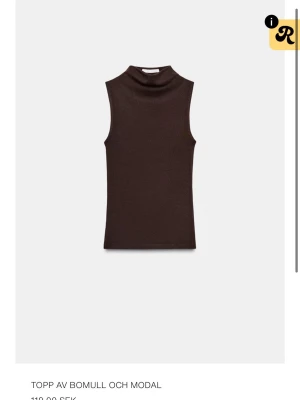 Mörkbrun ärmlös polotopp - Säljer en mörkbrun ärmlös polotopp i mjuk bomullsblandning. Toppen har en hög hals och sitter tight mot kroppen, perfekt att styla med jeans eller kjol. Enkel och stilren design utan mönster eller extra detaljer.