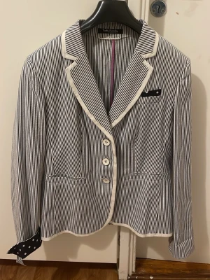 Randig kavaj från Betty Barclay - Snygg kavaj med smala svarta och vita ränder från Betty Barclay. Klassisk krage med vit kant, tre knappar framtill och fickdetaljer. Insidan av ärmsluten och bröstfickan har coola svarta detaljer med vita prickar. Perfekt för dig som vill sticka ut lite extra.