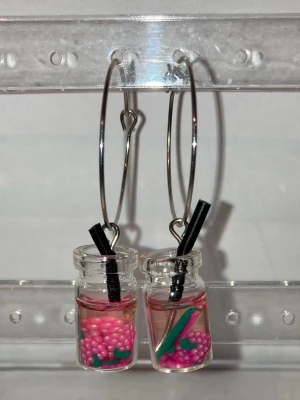 Örhängen  -  Handgjorda örhängen som görs av mig. Med rosa frukter i ett glas. Frakten är ca 22-100kr beroende på vikten på produkten . Kontakta mig om du vill köpa.