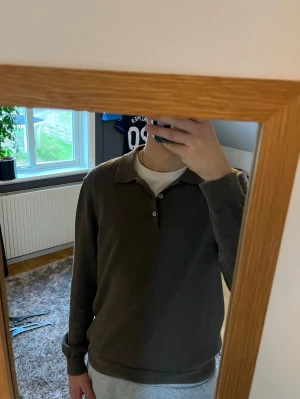 Mörkbrun pikétröja med lång ärm - Säljer en stilren mörkbrun pikétröja med lång ärm och klassisk krage. Tröjan har knappar vid halsen och är perfekt för dig som gillar en enkel men snygg look. Nypris är 600