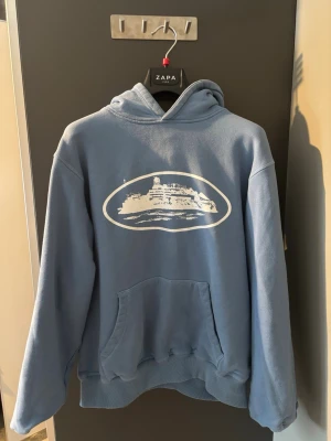 Corteiz hoodie  - En ljus blå varm Corteiz hoodie till våren och sommaren i bra pris nytt skick andvänd några gånger passar bra på killar och tjejer  