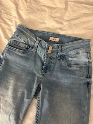 Ljusblå jeans från Nelly med rosa broderi - Säljer ett par ljusblå jeans från Nelly med snyggt rosa broderi på bakfickorna. Klassisk femficksmodell med dubbla knappar i midjan och har flared/ utsvängda ben. Jeansen har en skön passform och är tillverkade i mjukt denimtyg. Jeansen är lågmidjade och har bara användts 1 gång. Skicka om ni har frågor eller vill ha fler bilder!!💗