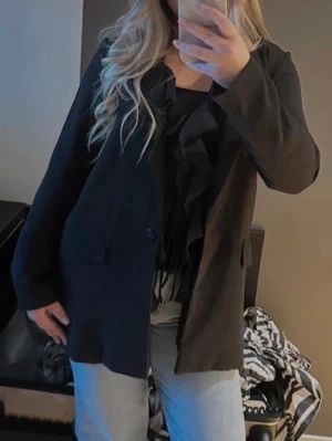 Kavaj - Säljer en svart kavaj från Gina Tricot med klassisk krage och enkel knäppning framtill. Kavajen har två fickor med lock och är rak i modellen. Perfekt att slänga över en topp för en clean och stilren look.