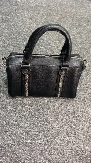 Svart handväska från Misako - Stilren svart handväska från Misako i syntetmaterial med två rejäla handtag och avtagbar axelrem. Väskan har silverfärgade dragkedjor och detaljer, samt två dekorativa dragkedjor på framsidan. Perfekt storlek för det viktigaste och har ett rymligt huvudfack.