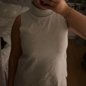 Vit ärmlös polotröja - Säljer en stilren vit ärmlös polotröja som är perfekt för lager-på-lager eller att bära som den är.  Perfekt för både vardag och fest! 🖤