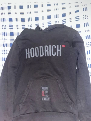 Svarta mjukisbyxor från Hoodrich - Svarta mjukisbyxor från Hoodrich med tryckt logga längs benet och bakficka med Hood-Tech-märke. Byxorna har normal passform, resår i midjan och dragkedja vid fickorna. Perfekta för en avslappnad streetwear-look.