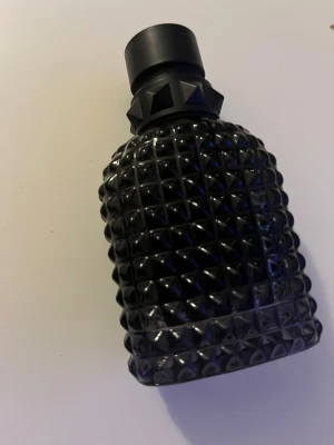 Valentino born in Roma  - Snygg parfym från Valentino i en svart, nitar-inspirerad flaska. Perfekt för dig som vill sticka ut och addera en lyxig touch till din stil. Passar dig som gillar trendiga accessoarer och vill ha något extra på hyllan.
