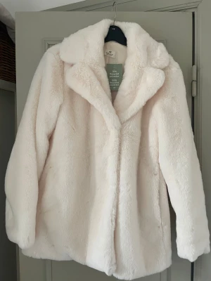 Vit pälsjacka från H&M, strl 164 - Säljer en fluffig och mjuk vit pälsjacka från H&M i storlek 164. Är som storlek S/M.  Jackan har bred krage, långärmad design och är tillverkad av återvunnen polyester. Perfekt för dig som vill ha en stilren och cozy look under kyliga dagar.