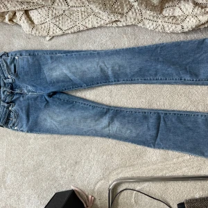 True Religion Becca Bootcut Jeans 26 - Säljer ett par ljusblå True Religion Becca Mid Rise Bootcut jeans i storlek 26. Klassisk femficksmodell med snygga detaljerade bakfickor och silverfärgade knappar. Jeansen har en bootcut passform och är tillverkade i mjukt denimtyg.