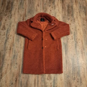 Rustfärgad teddyjacka från ONLY - Säljer en mysig och trendig teddyjacka från ONLY i en snygg rostbrun färg. Jackan har krage, knappar framtill och två fickor. Materialet är fluffigt och ger en cool oversized look, perfekt för höst och vinter. Jackan är långärmad och har slät insida.