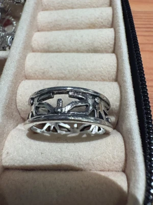 Silvrig ring med solmönster - Unik silvrig ring med ett coolt utskuret solmönster runt hela bandet. Ringen har en bred form och detaljer som ger den en edgy vibe. Perfekt för dig som gillar statement-smycken och vill sticka ut lite extra.